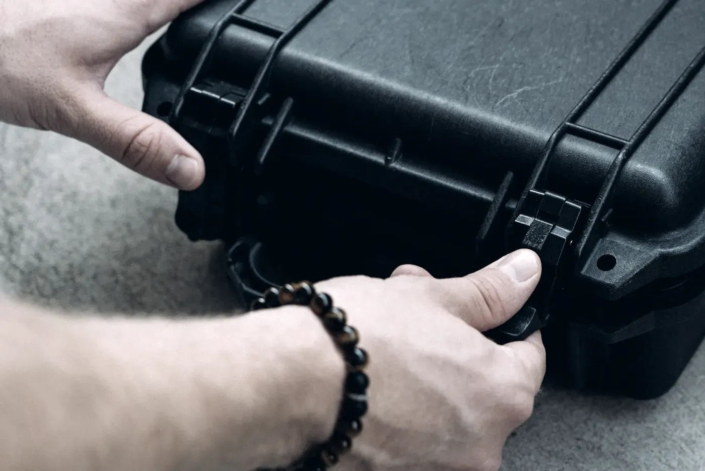 Hands closing the latches on a hard-shell protective case